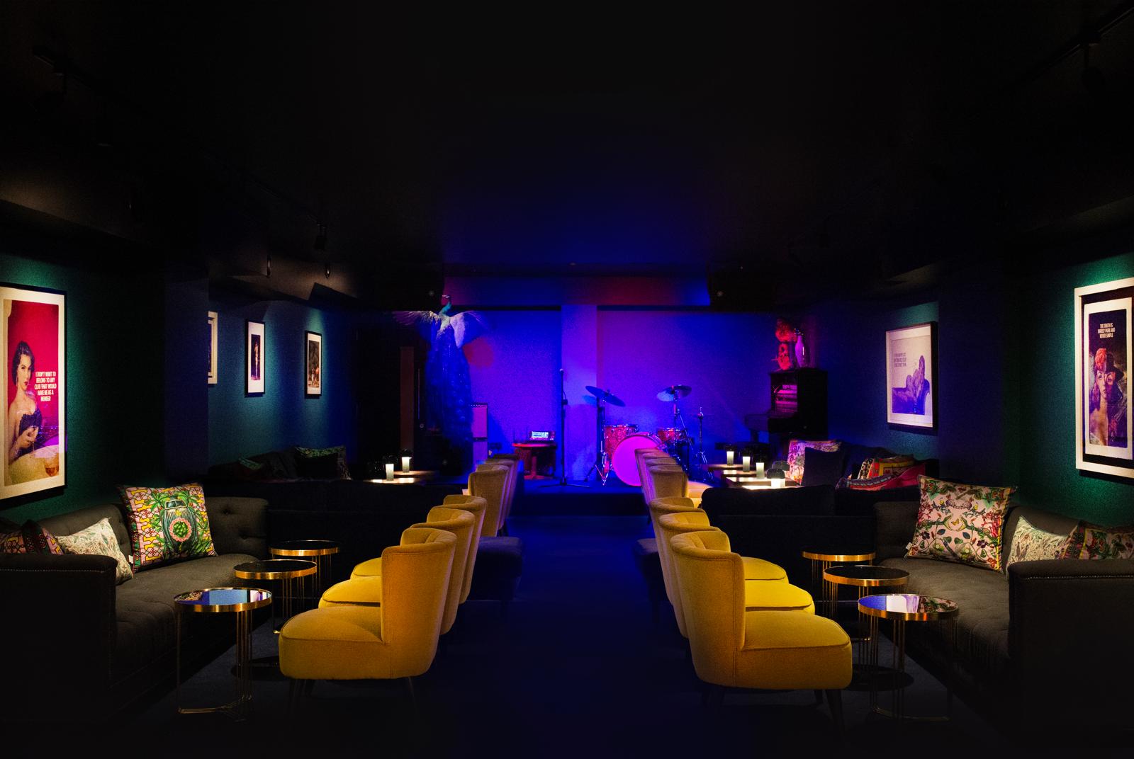 The HUX Kensington lounge set for live music, with velvet chairs facing the stage